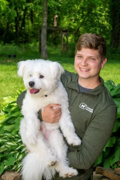 male dog trainer holding white dog